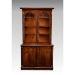 A Victorian mahogany cupboard bookcase, of small proportions, the flared, moulded cornice over a