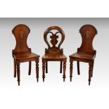 A pair of early Victorian walnut hall chairs, the arched, waisted backs with central carved shield