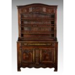 An early 19th century French Breton oak and brass dresser, the serpentine, moulded cornice over a