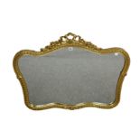 A gilt mirror of serpentine form decorated with flower and ribbon border. 23½ x 36ins (60 x 91.5cm)