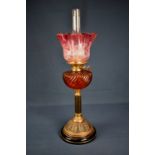 A Victorian brass oil lamp having brass column base, ruby glass font & floral etched shade,