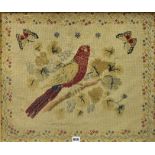 A framed tapestry of a bird on a branch with butterfly and foliate surround.