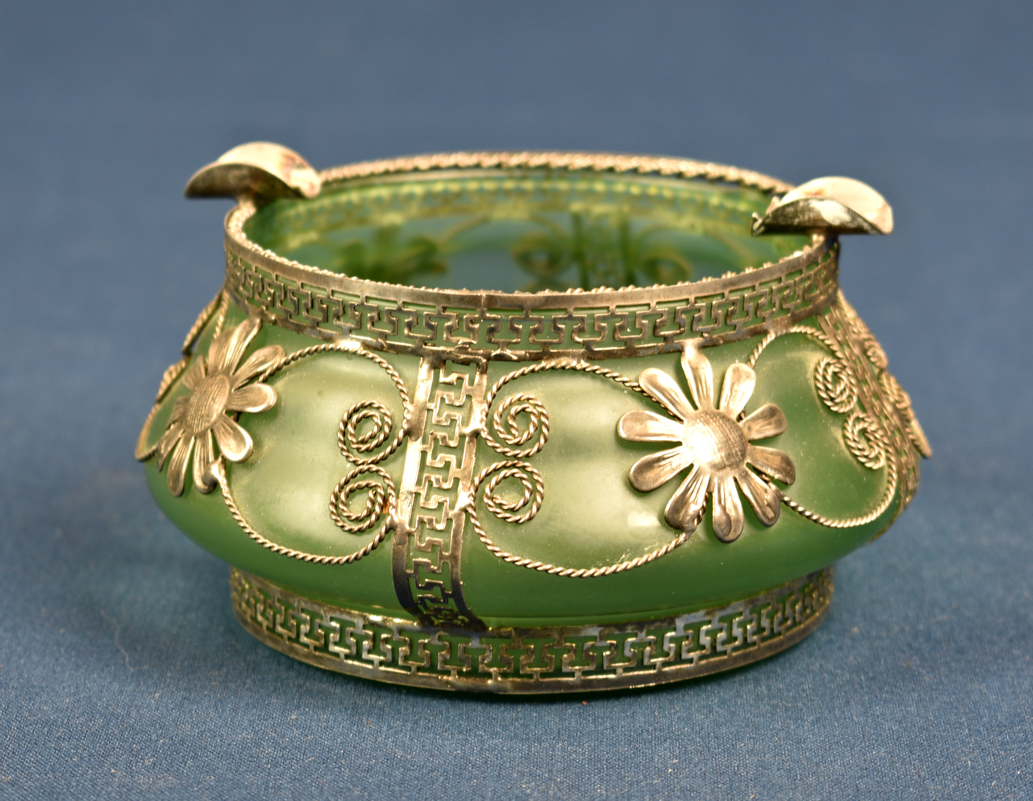 A green glass ashtray with metal overlay c. 1930's, of squat form, having metal overlay, decorated