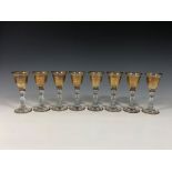 A set of eight mid-century gilded liqueur glasses the pale amber glass bell shaped bowls with