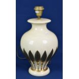A cream and gold table lamp with leaf pattern.