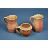 Two 18th century or earlier stoneware measures or tankards of typical form with flared neck and loop