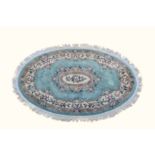 An oval Chinese wool rug, late 20th century, in pale blue and ivory with central floral medallion