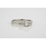 A platinum and diamond ring, The central princess cut stone flanked by diamond shoulders.