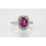 An 18ct cushion cut pink sapphire and diamond cluster ring, the central pink sapphire weighing