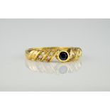 An 18ct yellow gold, diamond and sapphire ring, featuring a central, bevel set round cut sapphire of