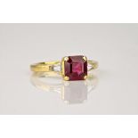 An 18ct yellow gold, ruby and diamond ring, the central, square cut ruby of deep red colouring and