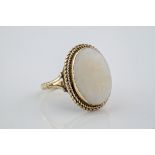A large 9ct yellow gold and opal ring, featuring an oval cut opal of 18mm in length and in a rubover