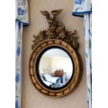 A 19th century Regency style convex mirror, with ebonised reeded slip and eagle surmount, 36¾in. (