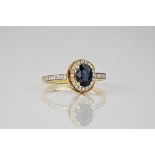 A 9ct yellow gold, sapphire and diamond cluster ring, the central, oval cut sapphire weighing