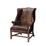An 18th century style dark brown leather wingback arm chair, late 20th century, the serpentine