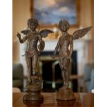 A matched pair of patinated bronze amorini, 20th century, one with a shield and bow on his back, a