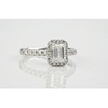 A platinum and emerald cut diamond cluster ring, the central diamond weighing approximately 1.