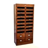 A 1950s honey oak haberdashery shop cabinet, the stepped, Art Deco style top over two banks of eight