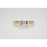 An 18ct yellow gold and diamond three stone ring, featuring a round cut centre stone of