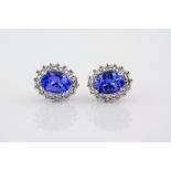 A pair of white gold, Tanzanite and diamond cluster earrings, featuring central oval cut