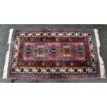 A Persian rug, the two square hooked medallions divided by three small dark blue shaped medallions