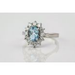 An 18ct white gold, aquamarine and diamond cluster ring, the central, oval cut aquamarine weighing