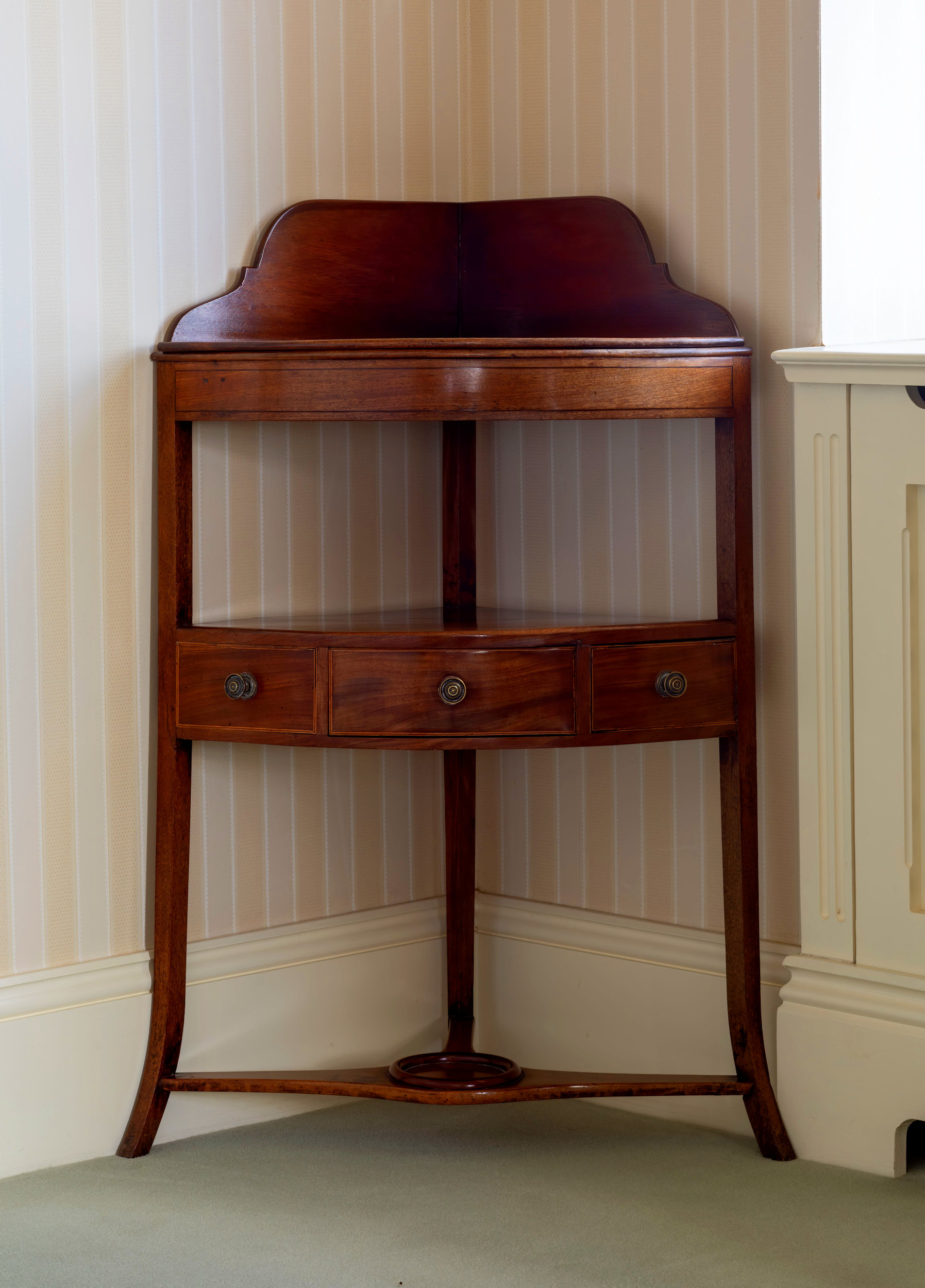 An early 19th century mahogany corner wash stand, the shaped back over a later fixed shelf, above