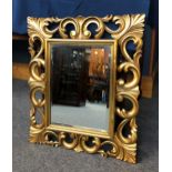 A Florentine style carved and pierced gilt wood mirror, with rectangular bevelled plate and