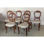 A set of six Victorian mahogany balloon back dining chairs, well reupholstered, raised on scroll