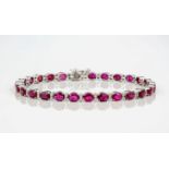 An 18ct white gold, ruby and diamond bracelet, featuring a row of deep red, oval cut rubies