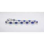 An 18ct white gold, sapphire and diamond line bracelet, featuring oval cut sapphires evenly
