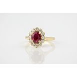 An 18ct yellow gold, ruby and diamond cluster ring, featuring a 1.25ct oval cut ruby surrounded by