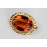 An 18ct gold and citrine brooch, the large, 25 x 18mm. orange citrine within a bright cut frame,