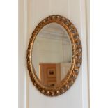 A 19th century oval giltwood mirror, with bevelled plate and pierced foliate frame, 27 x 23in. (68.5