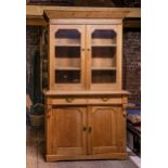 A Victorian waxed pine glazed kitchen dresser, the flared cornice over a pair of glazed doors