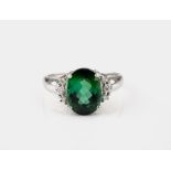 An 18ct white gold, green tourmaline and diamond ring, the oval cut tourmaline flanked by trios of