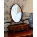 A George III mahogany serpentine box base toilet mirror, the oval plate over a tulipwood cross