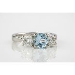 A platinum, aquamarine and diamond three stone ring, the central, round cut aquamarine weighing