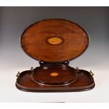 Three Edwardian mahogany inlaid tea / serving trays, the largest of oval form with wavy edge