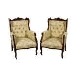 A pair of late Victorian carved walnut showframe wingback armchairs, the shaped foliate and