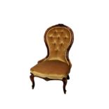 A Victorian walnut show frame nursing chair, with central floral carving to the top of the