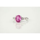 An 18ct white gold, pink sapphire and diamond ring, featuring an oval cut, vibrant pink sapphire