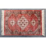 A small faux-silk Persian style rug, Belgian, the three graduated hooked medallions on a pale madder