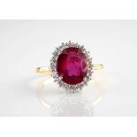 An 18ct yellow gold, ruby and diamond cluster ring, the central, oval cut ruby of deep crimson