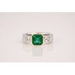 An 18ct white gold, emerald and diamond three stone ring, the central emerald of 1.9ct with two