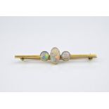 An antique 15ct yellow gold and opal brooch, the bar brooch within oval cabochon opal flanked by two