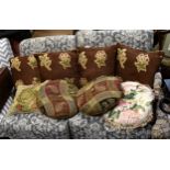 A set of four cushions, in brown velvet with wild flower and berry vignettes, together with a pair