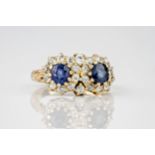 A yellow gold, sapphire and old cut diamond cluster ring, featuring two round cut sapphires