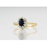 A 9ct yellow gold, sapphire and diamond cluster ring, the central, oval cut sapphire measuring 5mm