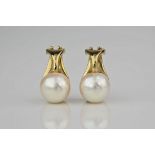 A pair of 18ct gold and cultured pearl clip earrings, each with a 7.5mm. pearl in a cupped mount. (